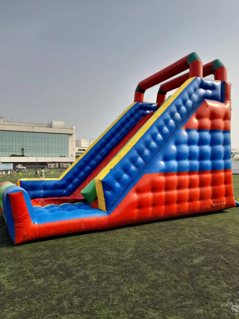 Foto de um tobogã inflável gigante com rampa de descida alta e cores vibrantes, um dos principais brinquedos para aluguel em festas de grande porte.